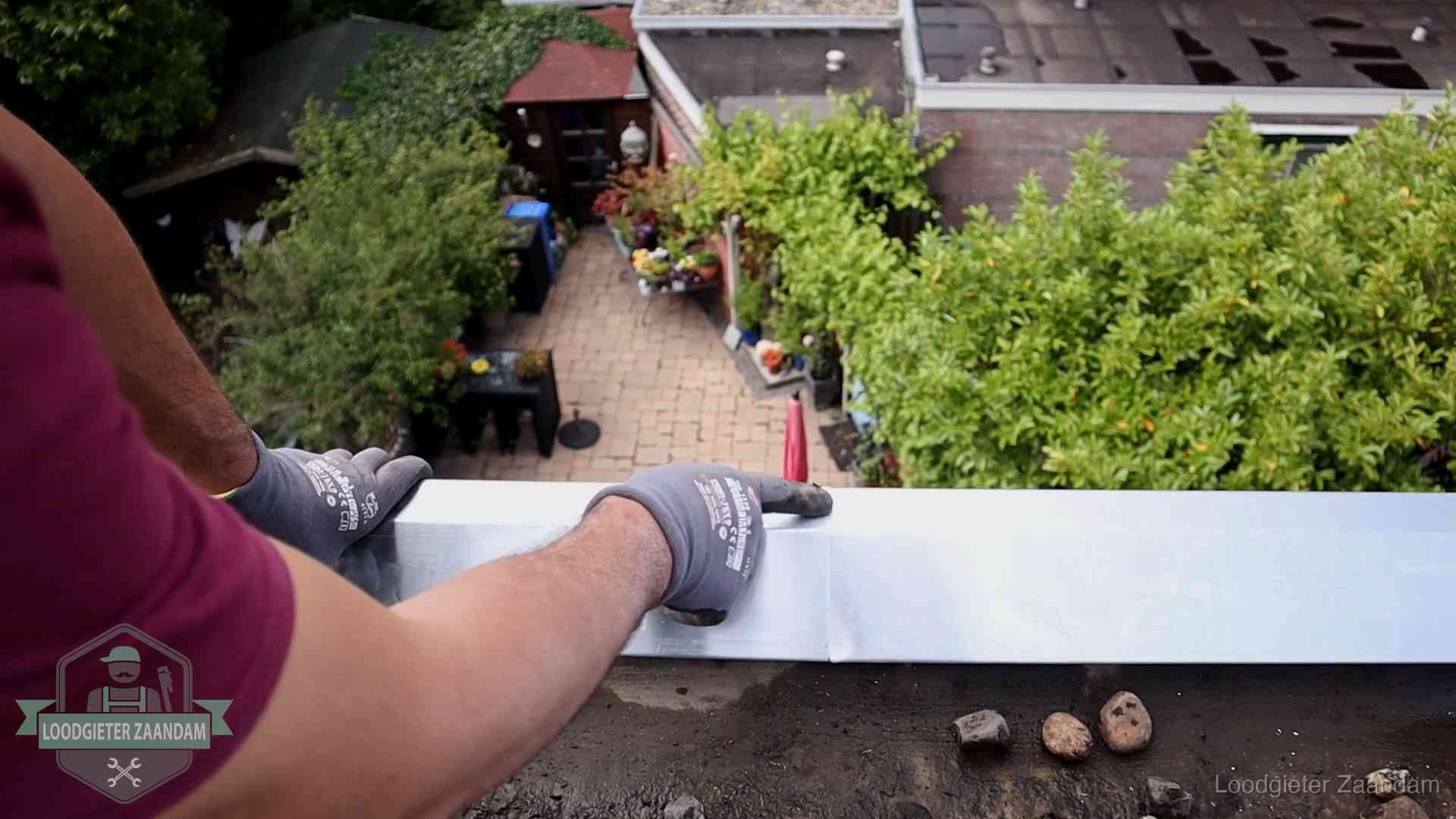 Daklekkage geregeld in Zaandam Vakman plaatst een daktrim op de dakrand van een woning in Zaandam