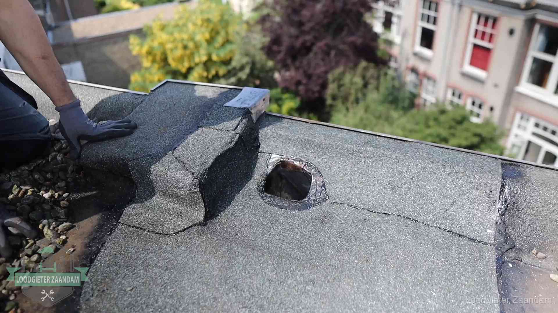 Daklekkage-inspectie op een plat dak in Zaandam Loodgieter inspecteert een beschadigd bitumen plat dak tijdens een daklekkage-inspectie in Zaandam