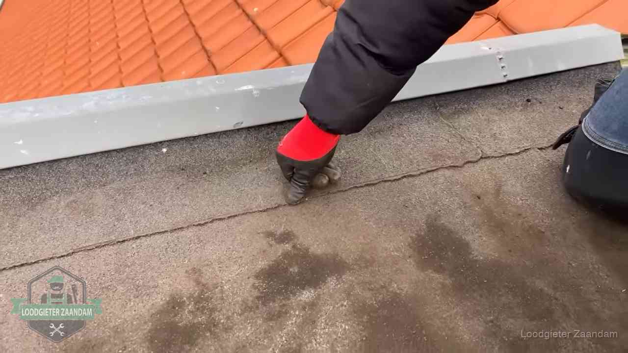 Lekkage bij de naad van een plat dak in Zaandam Vakman wijst een naad met vochtplekken aan op een bitumen plat dak in Zaandam
