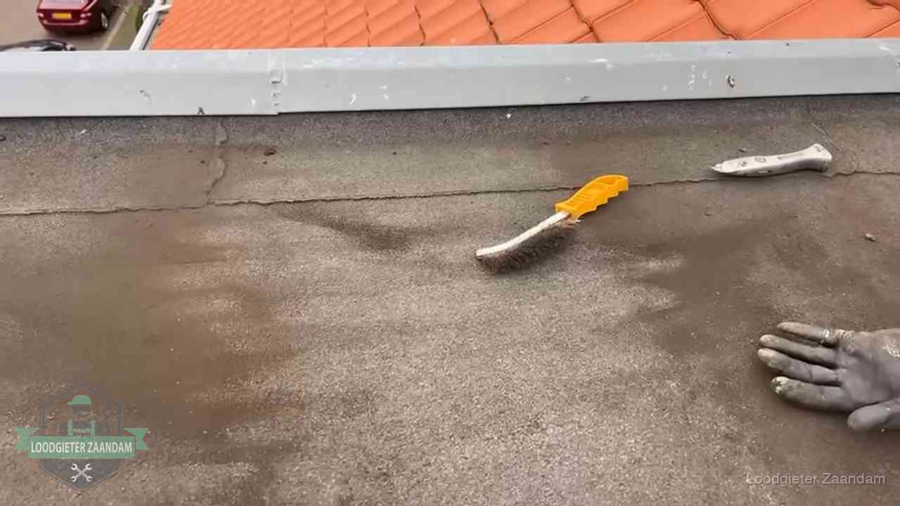 Kosten van daklekkage-reparatie in Zaandam Dakdekker bereidt een bitumen plat dak voor op reparatie bij de daktrim in Zaandam