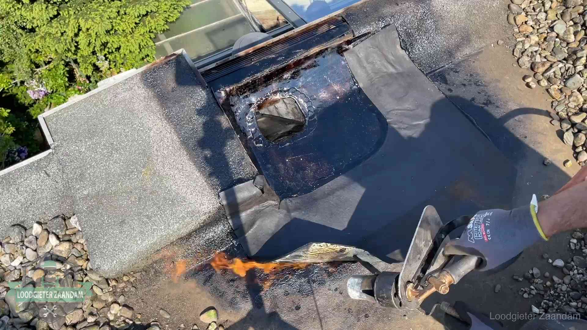 Daklekkage repareren in Zaandam Dakdekker brandt bitumen rond een doorvoer tijdens een daklekkage-reparatie in Zaandam