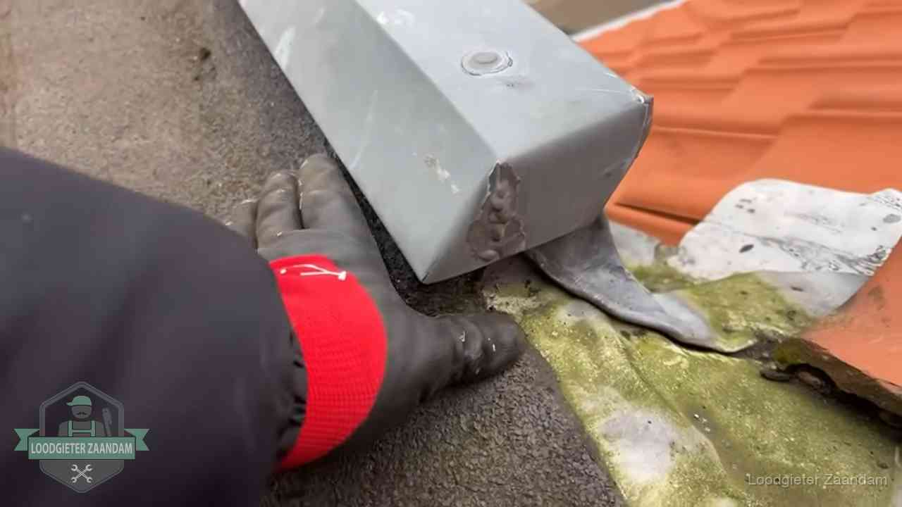 Hemelwaterafvoer en dakgoot controleren in Zaandam Controle van een zinken hemelwaterafvoer met loodslab bij dakpannen in Zaandam