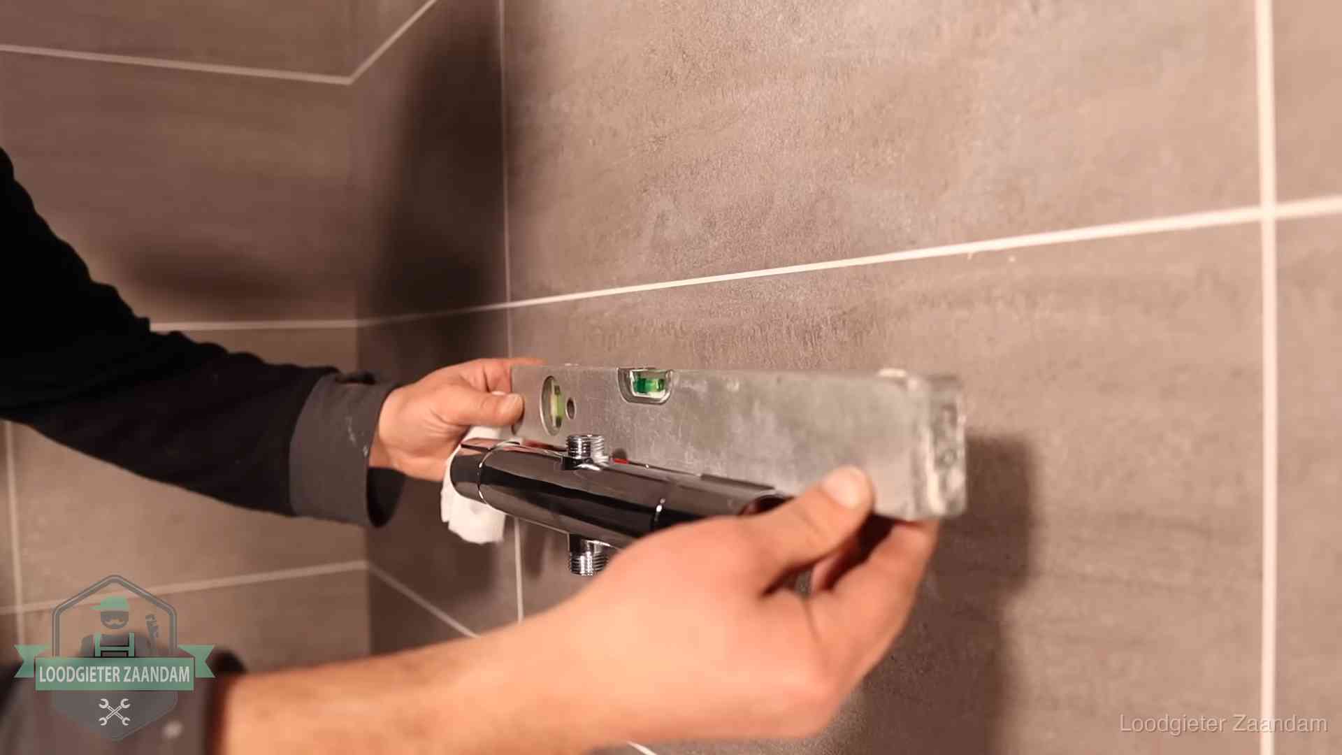 Loodgietersbedrijf voor sanitair in Zaandam Loodgieter lijnt een douchekraan uit met een waterpas in een woning in Zaandam