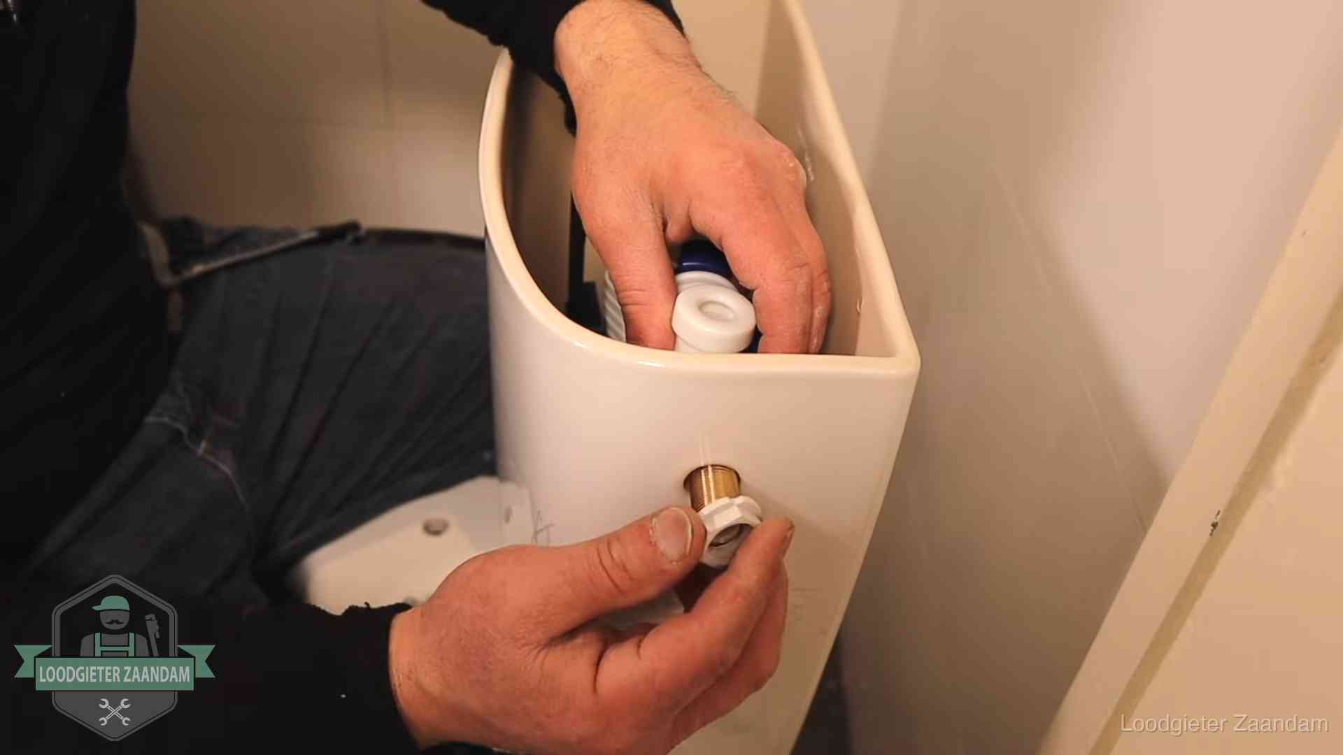 Loodgieter monteert de vlotterkraan van een stortbak bij een toilet in Zaandam