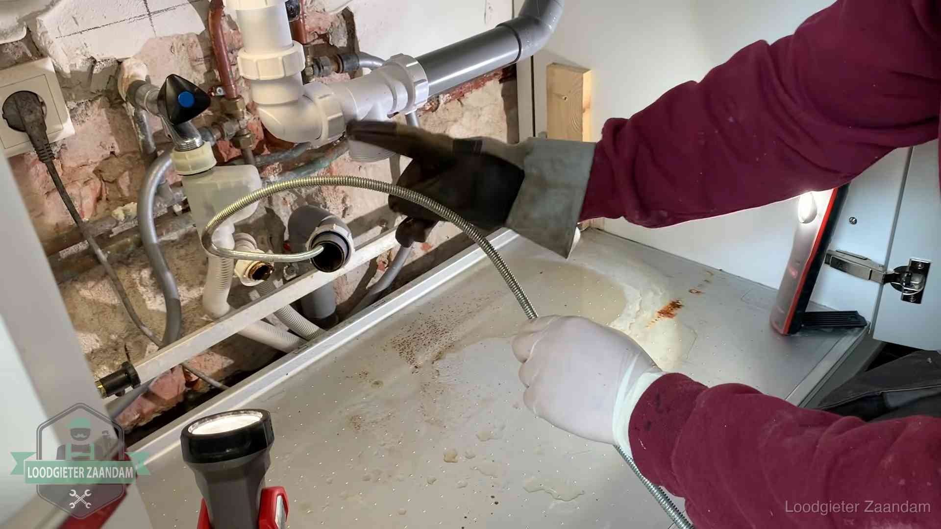 Spiraal of hogedruk in Zaandam Ontstoppingsveer gaat in een geopende sifonaansluiting onder het aanrecht in Zaandam