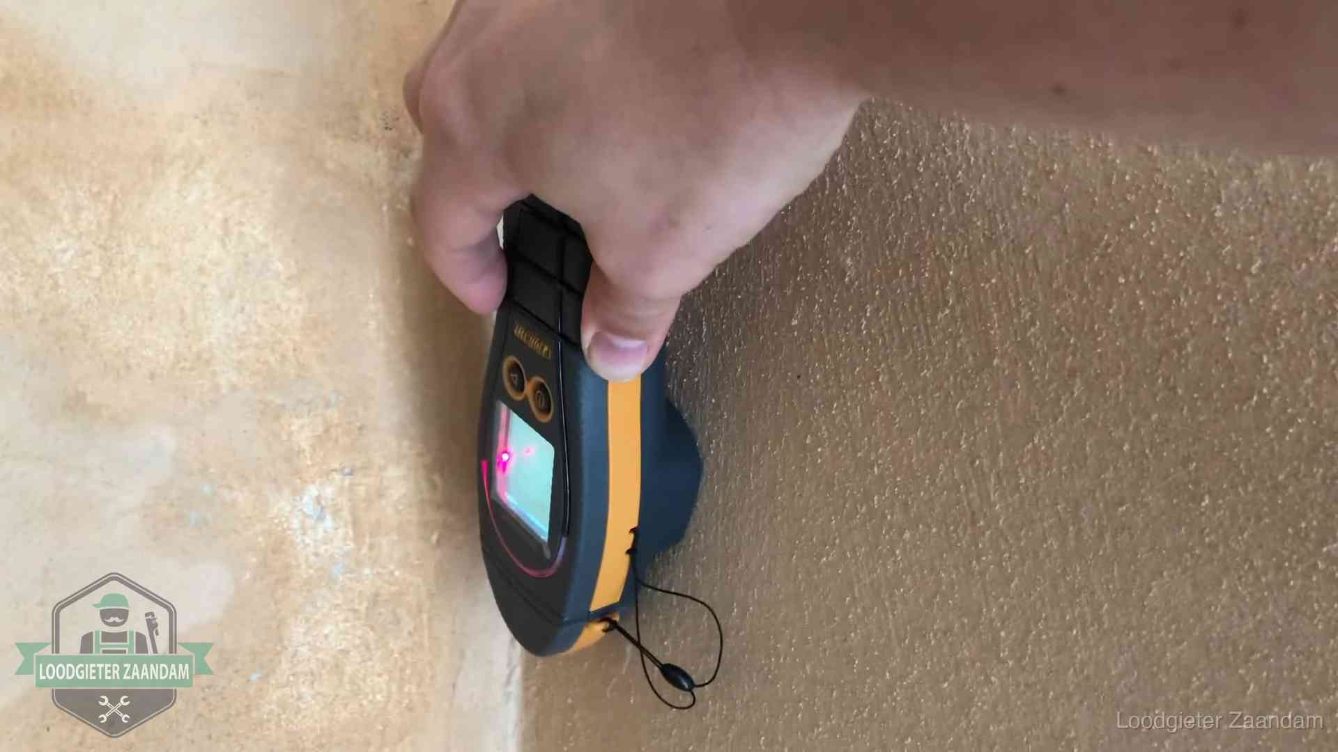Daklekkage opsporen zonder hakwerk in Zaandam Vochtmeter tegen een muur met vochtplekken tijdens het opsporen van een daklekkage in Zaandam
