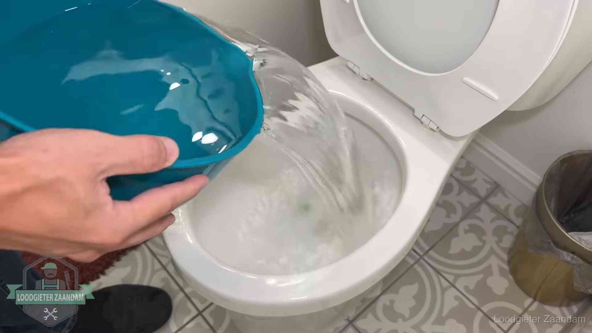 Warm water wordt voorzichtig in de wc-pot gegoten in Zaandam