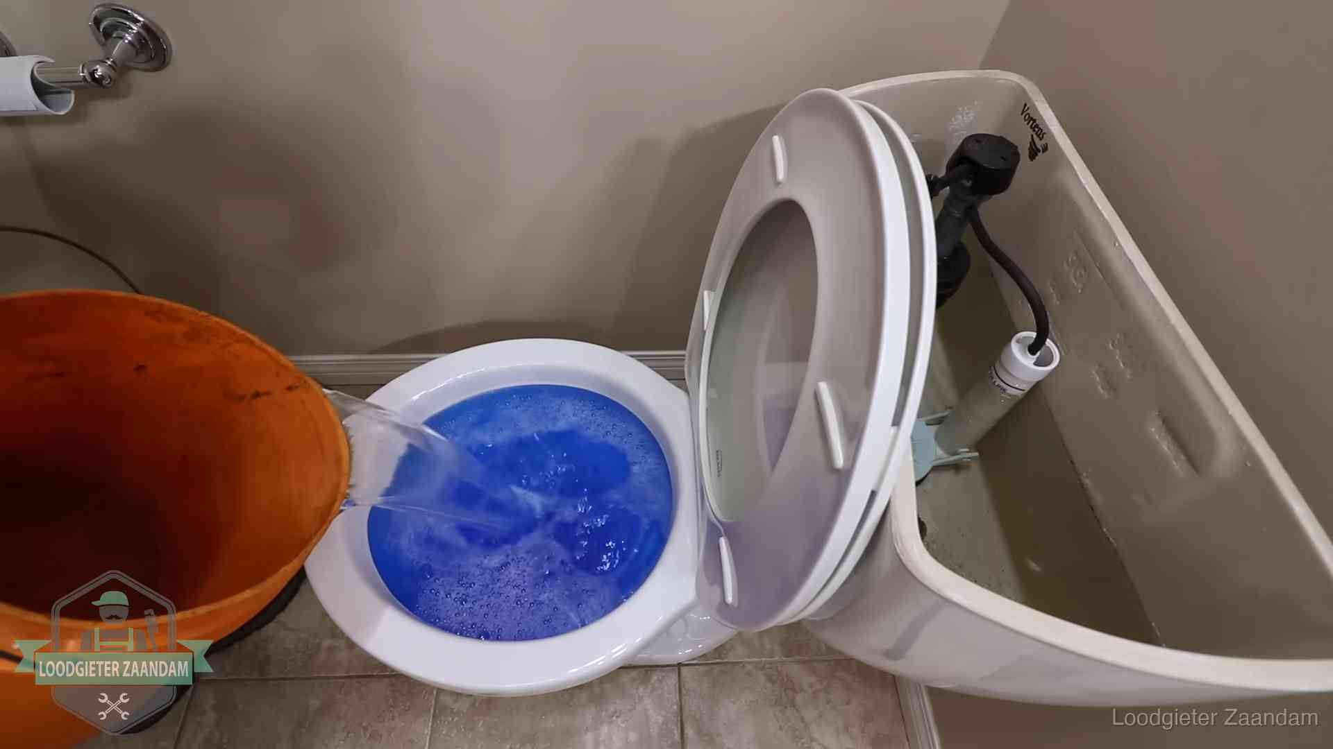 Water bij de wc-pot wordt met een emmer weggewerkt om schade te beperken in Zaandam